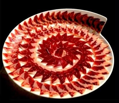 Fuente con lonchas de jamón colocadas en triángulos y espiral geométrica