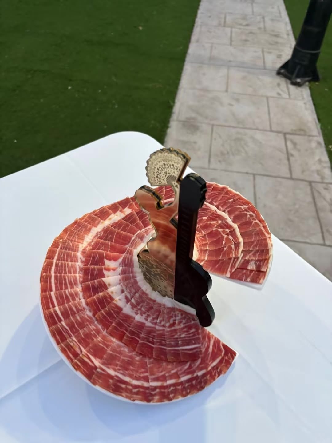 Soporte de presentación con lonchas de jamón y una silueta flamenca decorativa