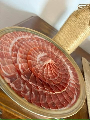 Lonchas finas de jamón curado en capas concéntricas sobre una fuente ovalada
